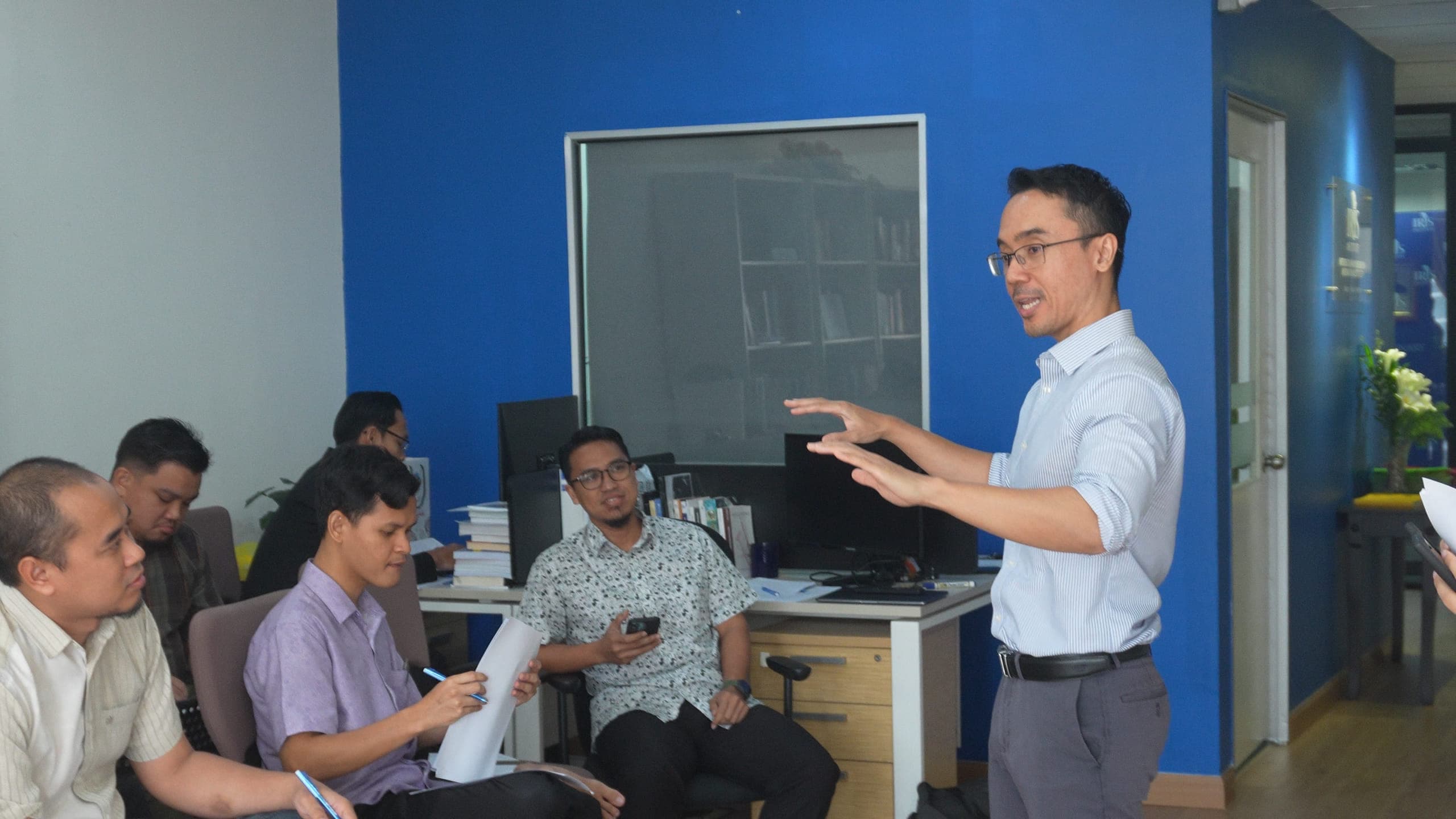 Irwan Hanish standing and gesturing while delivering a professional training session.